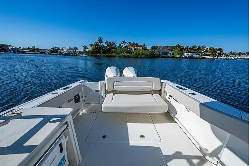 Slide: The Image of 2019 Boston Whaler 270 Vantage boat on calm water, clear blue sky, and scenic shoreline. - 18