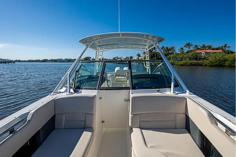 Slide: The Image of 2019 Boston Whaler 270 Vantage boat on calm water, clear sky, and lush shoreline. - 9
