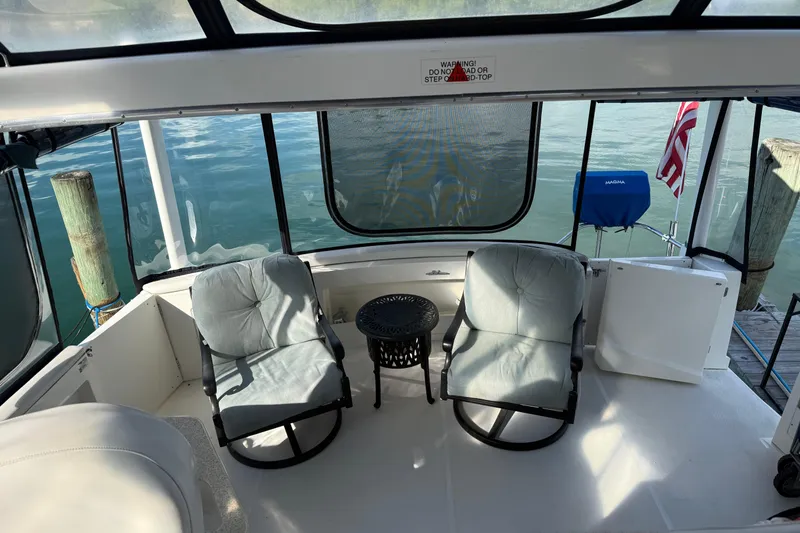 Slide: The Image of 2005 Silverton 43 Motor Yacht deck with chairs and table, overlooking serene water. - 18