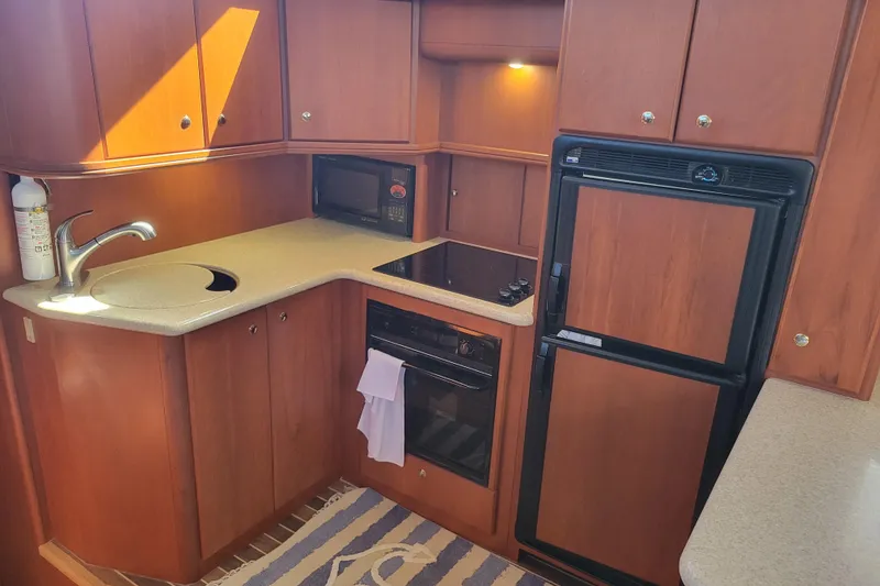 Slide: The Image of 2005 Silverton 43 Motor Yacht kitchen with wood cabinetry, sink, stove, microwave, and refrigerator. - 30