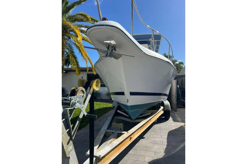 Slide: The Image of 1997 Cobia 244 Center Console boat on trailer, parked outdoors under clear blue sky. - 21