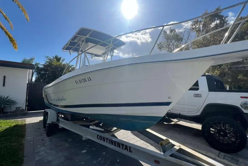 Slide: The Image of 1997 Cobia 244 Center Console boat on trailer, parked outdoors under sunny sky. - 3