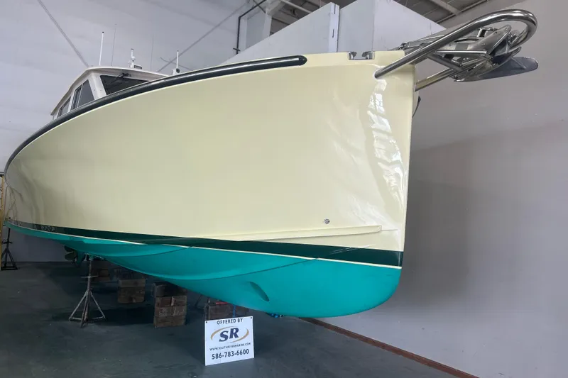 Slide: The Image of 2007 True North 38 Heritage boat in showroom, cream and teal hull, displayed on stands. - 1