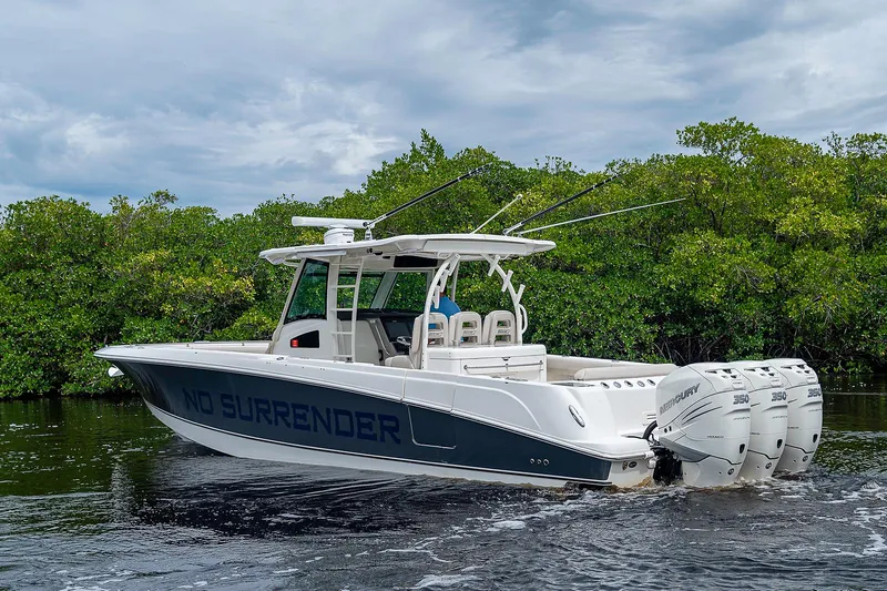 Slide: The Image of 2017 Boston Whaler 370 Outrage boat on water, lush greenery background. - 11