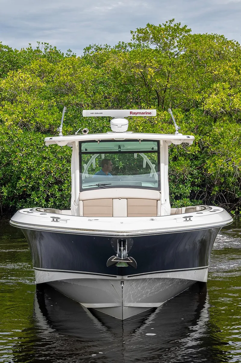 Slide: The Image of 2017 Boston Whaler 370 Outrage boat on water, surrounded by lush greenery. - 14