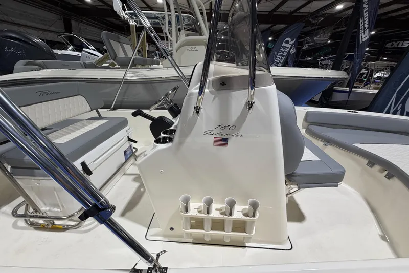 Slide: The Image of 2026 Pioneer 180 Islander boat interior with seating and console, displayed indoors. - 7