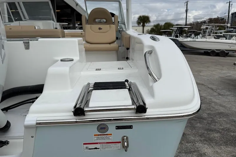Slide: The Image of 2026 Sea Pro 240 Dual Console boat with swim ladder and seating, docked outdoors. - 11
