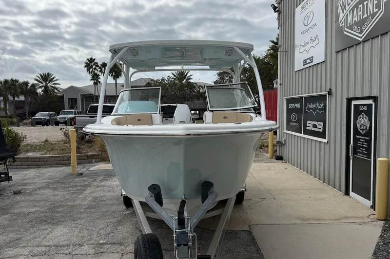 Slide: The Image of 2026 Sea Pro 240 Dual Console boat parked outside a marine service shop. - 2