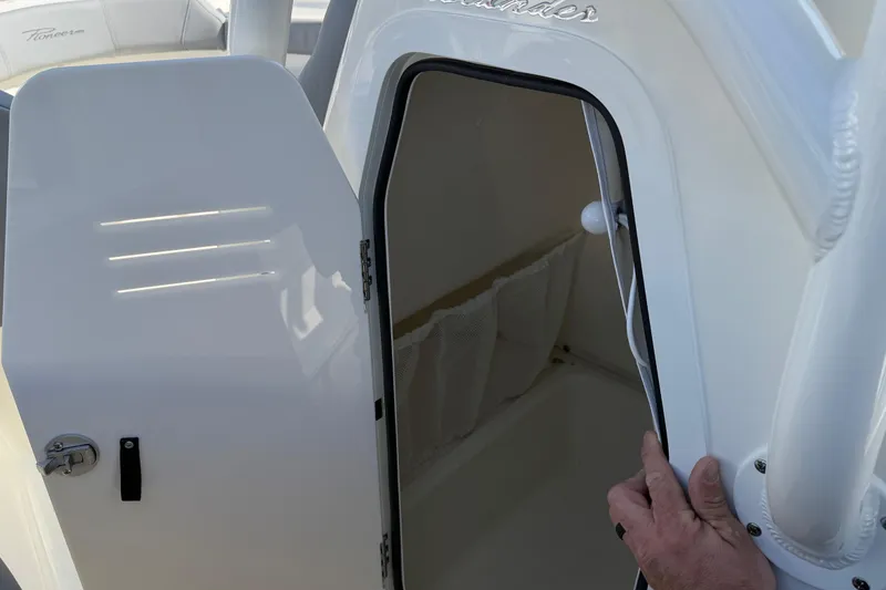 Slide: The Image of 2026 Pioneer 202 Islander boat cabin door, partially open, showing interior storage. - 22
