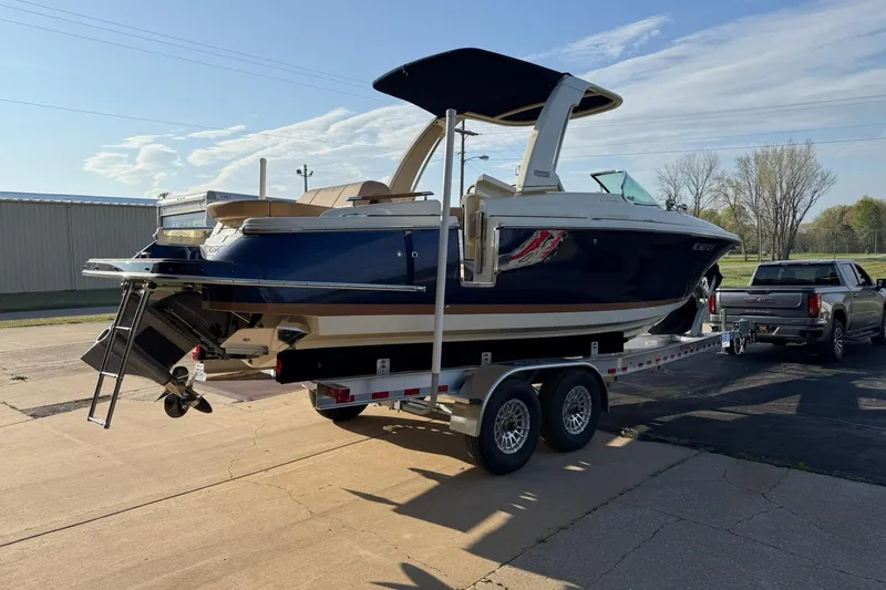 Slide: The Image of 2025 Chris-Craft Launch 28 GT boat on trailer, parked outdoors, with a truck. - 46