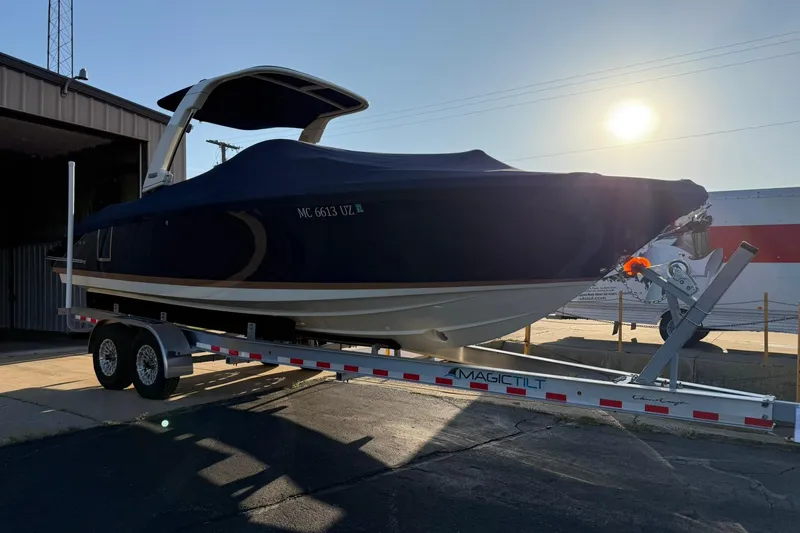 Slide: The Image of 2025 Chris-Craft Launch 28 GT boat on trailer, covered, in sunlight near a building. - 47