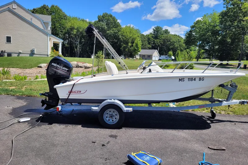Slide: The Image of 2010 Boston Whaler 150 Super Sport boat on trailer, parked outdoors on sunny day. - 2