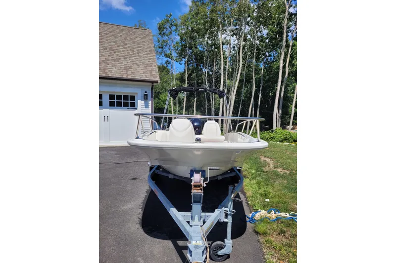 Slide: The Image of 2010 Boston Whaler 150 Super Sport boat on trailer, parked near garage and trees. - 3