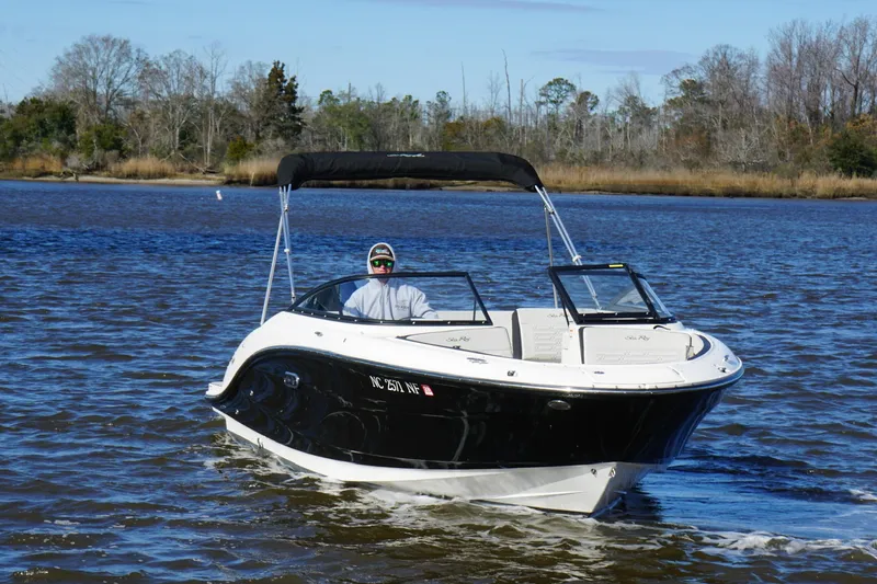 The Image of 2025 Searay SPX210 boat cruising on a calm lake with trees in the background. - 1