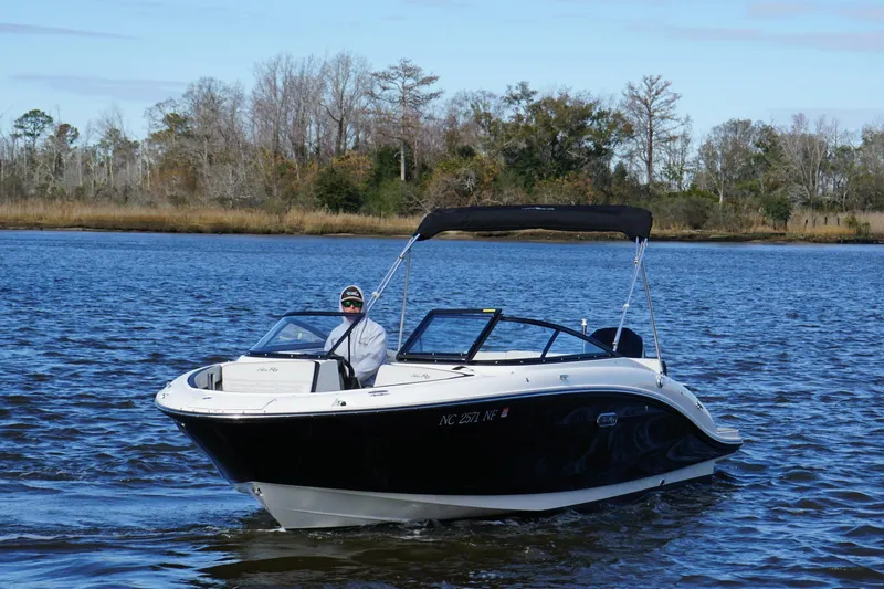 Slide: The Image of 2025 Searay SPX210 boat cruising on a calm lake with trees in the background. - 11