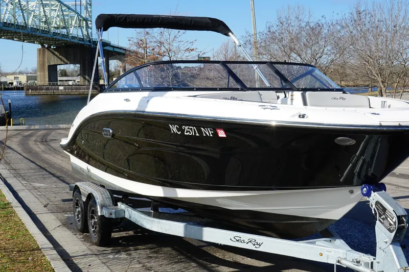 Slide: The Image of 2025 Searay SPX210 boat on trailer near bridge and waterway. - 15