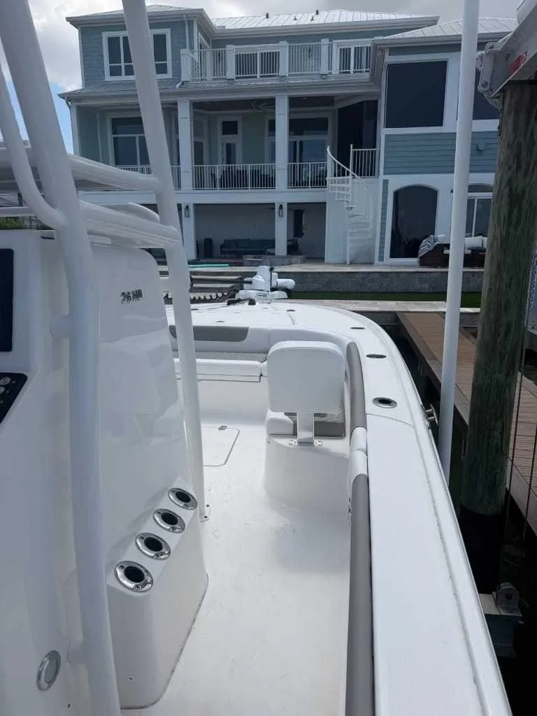 Slide: The Image of A modern Caymas 26 HB boat from 2026 docked in front of a large house. - 4