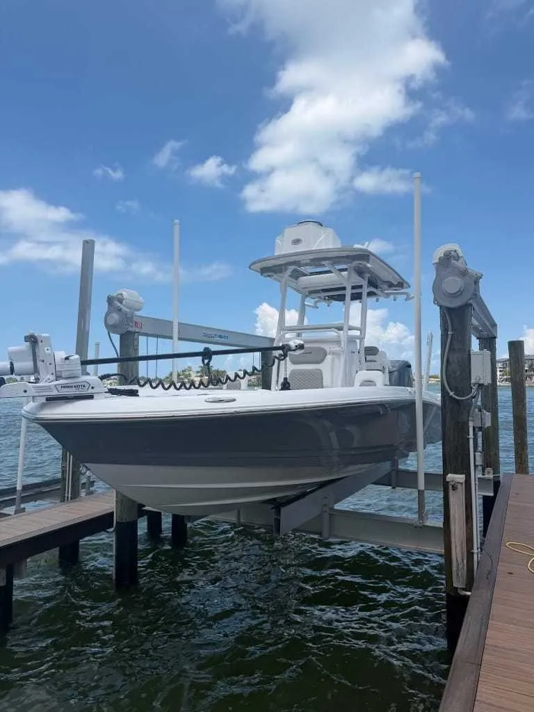 The Image of A 2026 Caymas 26 HB boat is on a lift above the water. The sky is clear. - 0