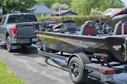 Slide: The Image of 2022 Ranger RT198P Fishing Package on trailer, hitched to a truck, parked outdoors. - 3