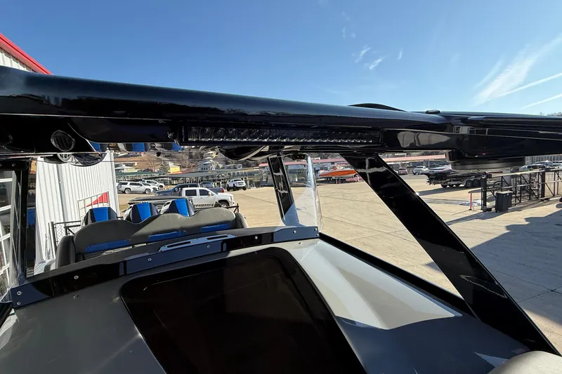 Slide: The Image of 2026 Sunsation 34 CCX boat with sleek black canopy and modern seating, parked outdoors. - 19