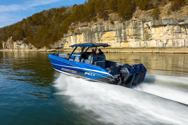 Slide: The Image of 2026 Sunsation 34 CCX speedboat cruising on a scenic lake with rocky cliffs. - 35