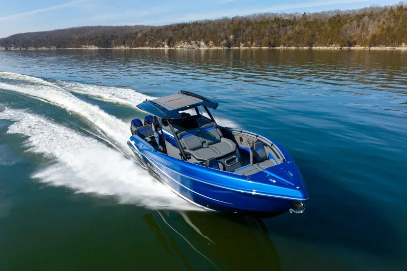 Slide: The Image of 2026 Sunsation 34 CCX speedboat cruising on a serene lake with forested shoreline. - 47