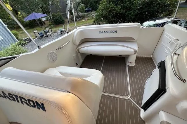 Slide: The Image of 2003 Glastron GS 279 boat interior with white seating and wood-patterned flooring. - 5
