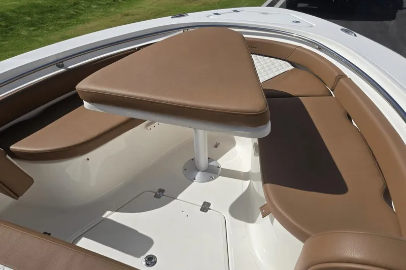 Slide: The Image of 2026 Pioneer 222 Islander boat interior with brown cushioned seating and table. - 10