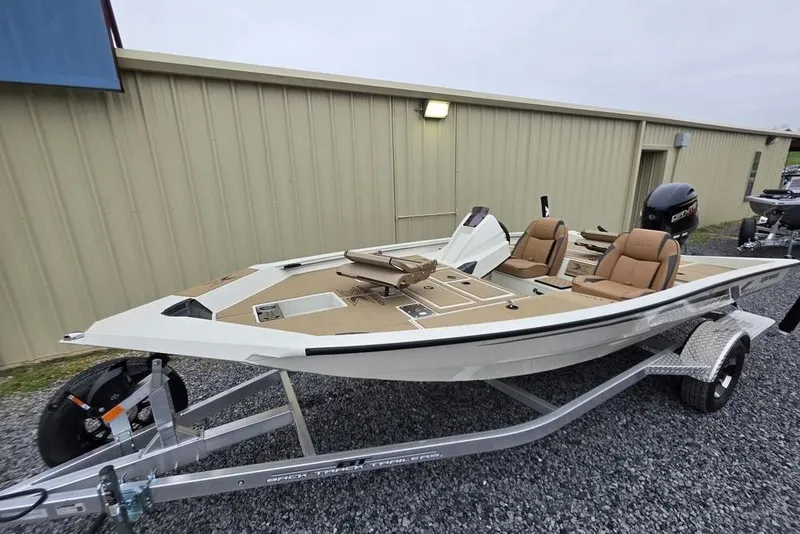 Slide: The Image of 2026 Xpress H18C Crappie boat on trailer, beige interior, parked outside metal building. - 16