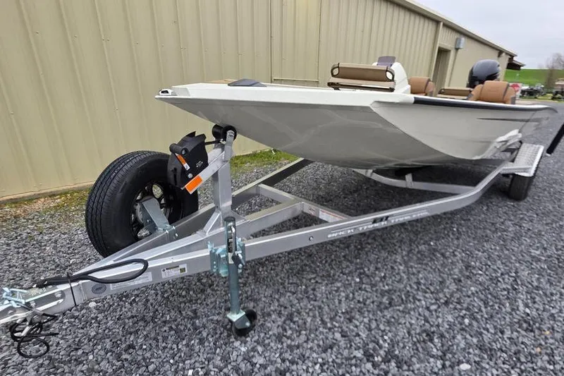 Slide: The Image of 2026 Xpress H18C Crappie boat on trailer, parked on gravel near a building. - 2