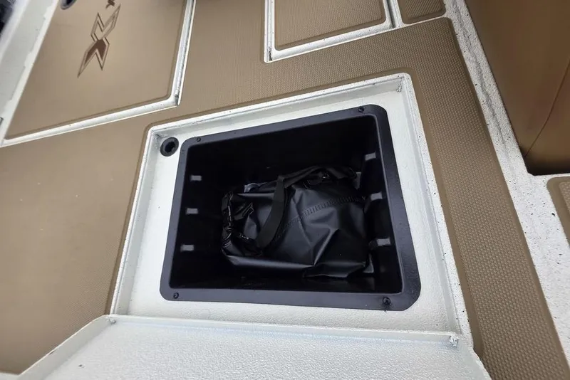 Slide: The Image of Storage compartment in 2026 Xpress H18C Crappie boat, featuring a black bag inside. - 9