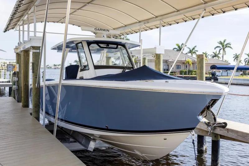 The Image of 2023 Pursuit S 328 Sport boat docked under canopy, waterfront view. - 1