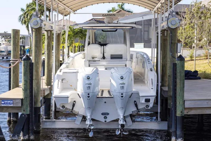 Slide: The Image of 2023 Pursuit S 328 Sport boat docked with twin engines, under a canopy. - 3
