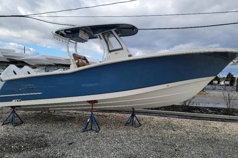The Image of 2026 Pioneer 270 Pelagic boat on stands, blue hull, cloudy sky background. - 0