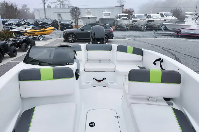 Slide: The Image of 2021 Tahoe T16 boat interior with gray and green seating, parked near other boats. - 10