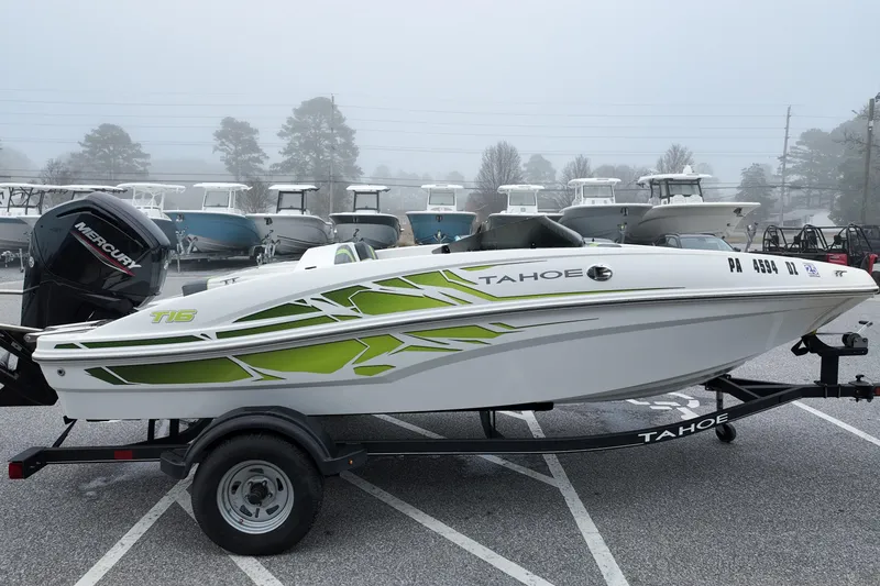 Slide: The Image of 2021 Tahoe T16 boat with green accents on a trailer in a foggy marina. - 2