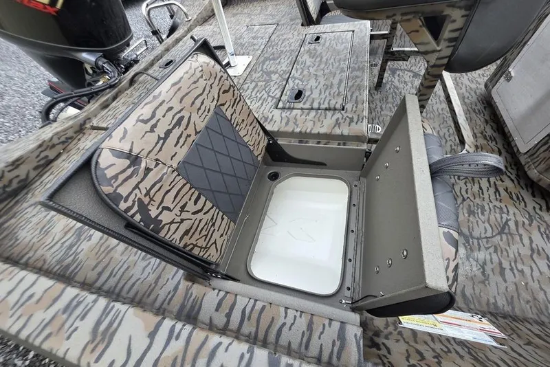 Slide: The Image of 2026 Xpress H20B Bay boat with camo seating and storage compartment open. - 11