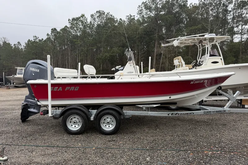 The Image of 2007 Sea Pro SV1900CC Bay Boat on trailer, red hull, Yamaha outboard, parked outdoors. - 1