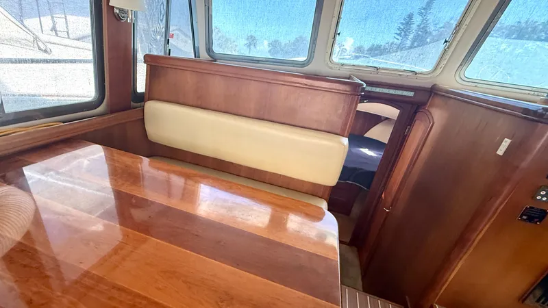 Slide: The Image of Interior of a 2004 Mainship 400 Trawler with wooden table and bench seating. - 18