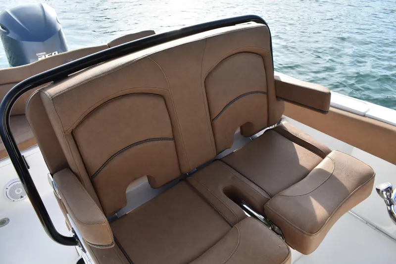 Slide: The Image of 2020 Sea Hunt Ultra 235 SE boat seating with brown upholstery and water backdrop. - 19