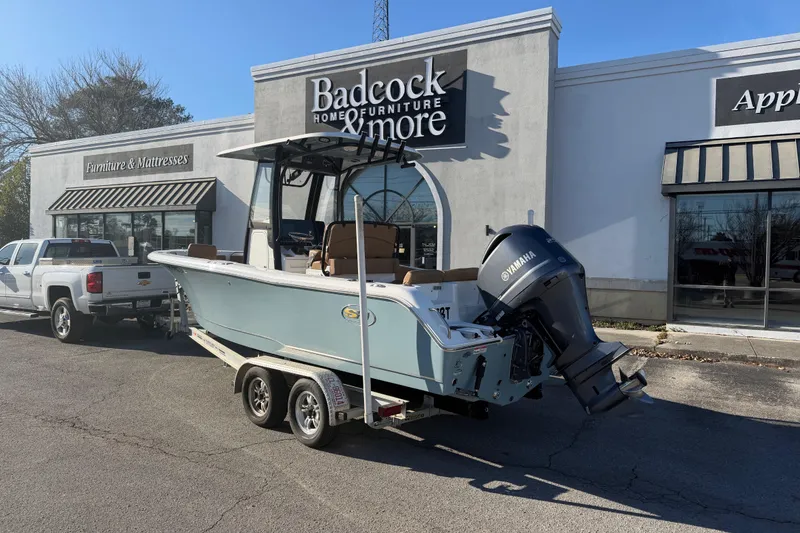 Slide: The Image of 2020 Sea Hunt Ultra 235 SE boat cruising on a serene lake near waterfront homes. - 2