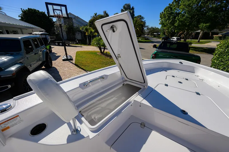 Slide: The Image of 2023 Sportsman Masters 267 Bay Boat with open storage compartment, parked in a driveway. - 14