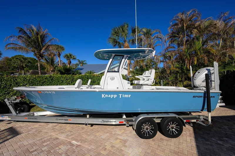 Slide: The Image of 2023 Sportsman Masters 267 Bay Boat on trailer, surrounded by tropical foliage. - 2