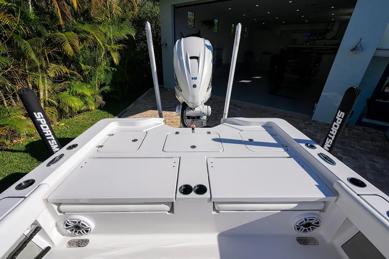 Slide: The Image of 2023 Sportsman Masters 267 Bay Boat with outboard motor, docked near lush greenery. - 21