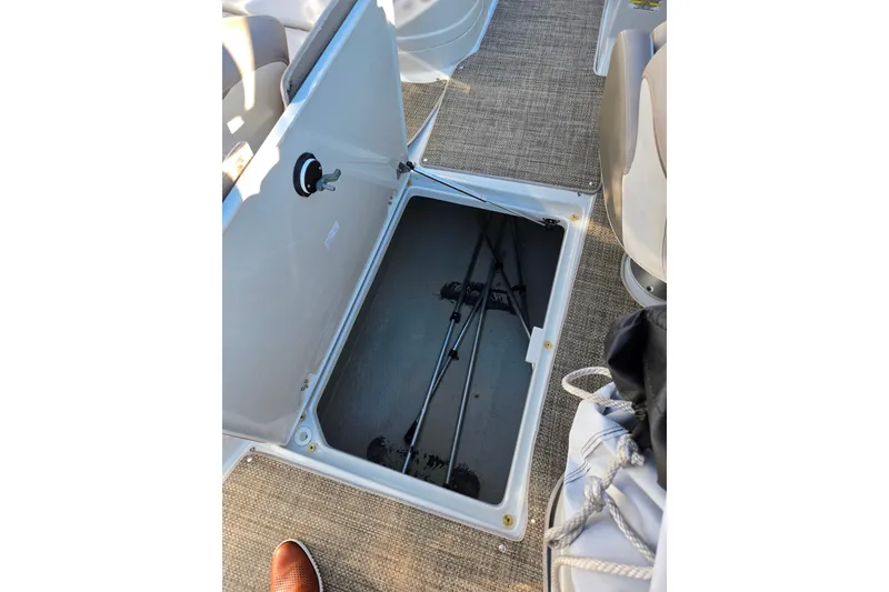 Slide: The Image of Open storage compartment on 2018 Crownline 275 SS boat, revealing fishing rods inside. - 28