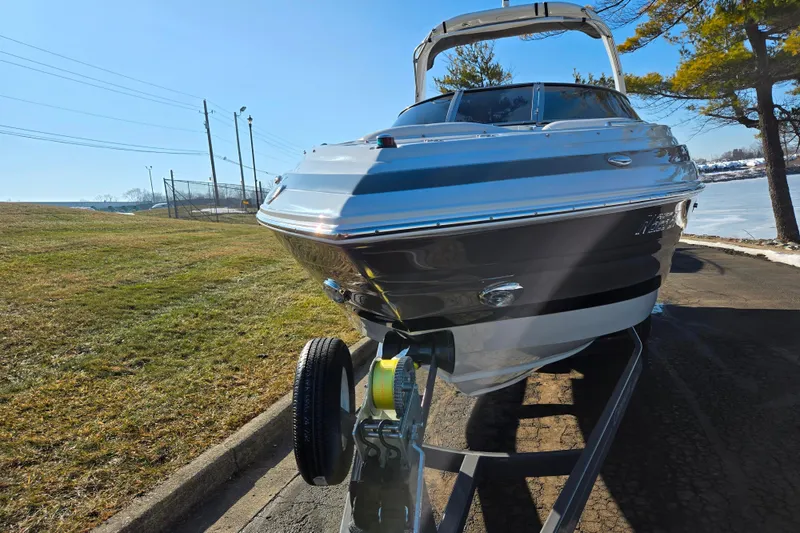 Slide: The Image of 2018 Crownline 275 SS boat on trailer, parked near grassy area and trees. - 6