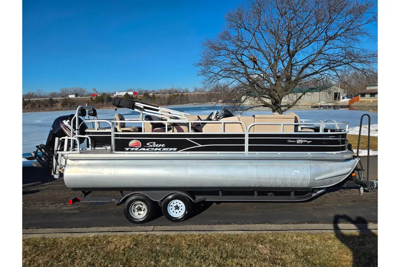 Slide: The Image of 2018 Sun Tracker Bass Buggy 18 DLX pontoon boat on trailer by a lake. - 12