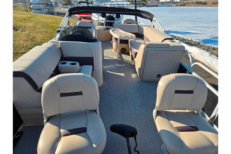 Slide: The Image of 2018 Sun Tracker Bass Buggy 18 DLX pontoon boat interior with beige seating and lake view. - 14