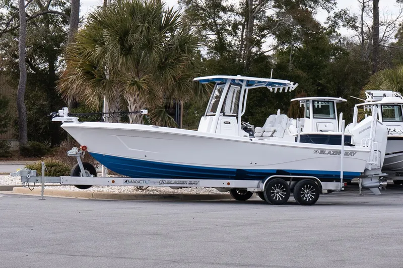 The Image of 2026 Blazer Bay Makaira 2800 boat on trailer, parked outdoors with trees in background. - 1
