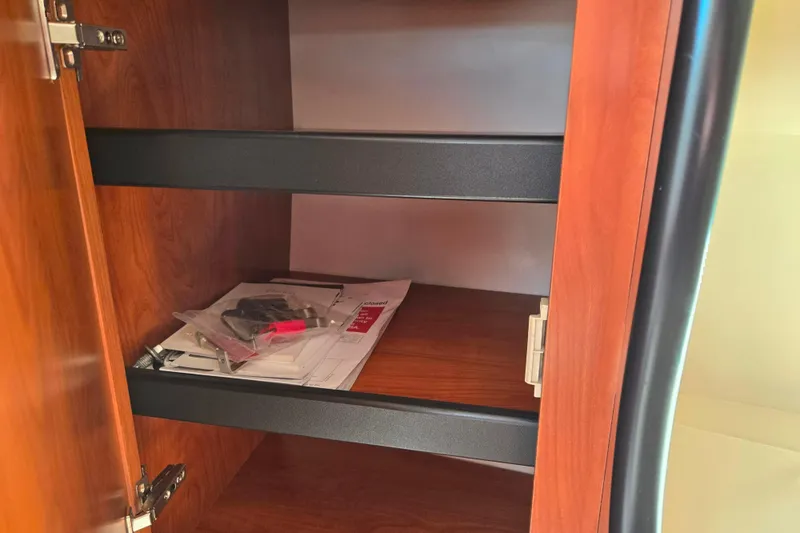 Slide: The Image of Wooden cabinet interior with shelves, containing documents and a small bag, in a 2007 Rinker 262 Captiva Cuddy. - 20
